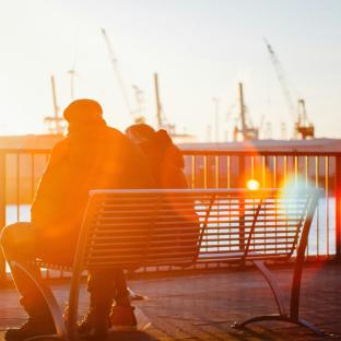 Older couple sitting on a bench at sunset