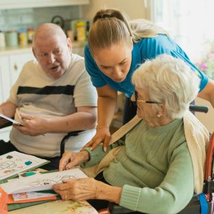 two older persons being supported by a care worker